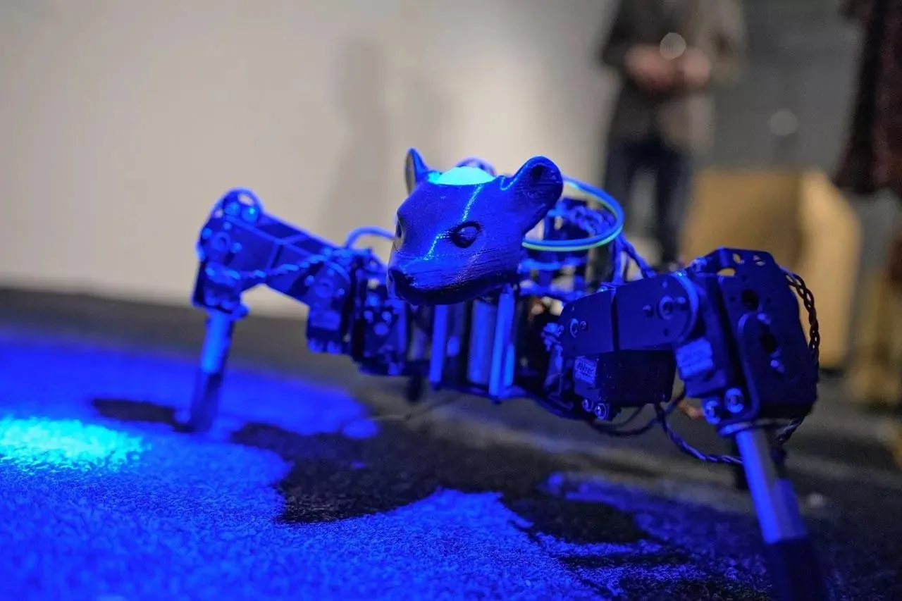 BioComputation Robots installation view showing small mouse-like robots on a white plinth in a gallery setting.