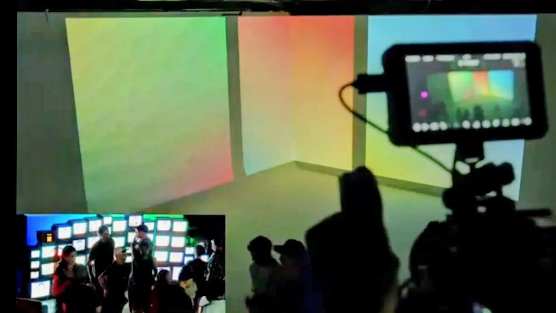 Documentation view of Memory Compression displayed across three large luminous screens at RGBMTL, with visitors and a camera visible in the foreground.